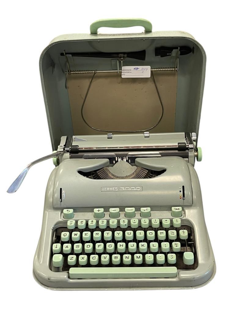 VINTAGE HERMES 3000 TYPEWRITER WITH CASE AND BRUSH ACCESSORIES: KNOWN AS A HIGHLY SOUGHT OUT VINTAGE TYPEWRITER, IN MINT GREEN WITH A CURVED SHELL FOR PORTABILITY, MADE IN THE MID 1950'S AND 1960'S, SOME REFERRED TO IT AS THE ROLLS ROYCE OF TYPEWRITERS 13" X