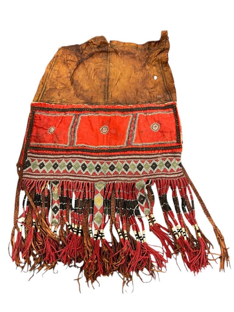 NORTH AFRICA TUAREG LEATHER AND TEXTILE PARTIAL SADDLE BAG: SADDLE APPEARS TO HAVE BEEN UNFINISHED OR ATTEMPT TO PRESERVE, LEATHER IS BEGINNING TO BECOME BRITTLE, FEATURES HAND CRAFTED FRINGE WITH DIAMOND DESIGN 14" X 22"