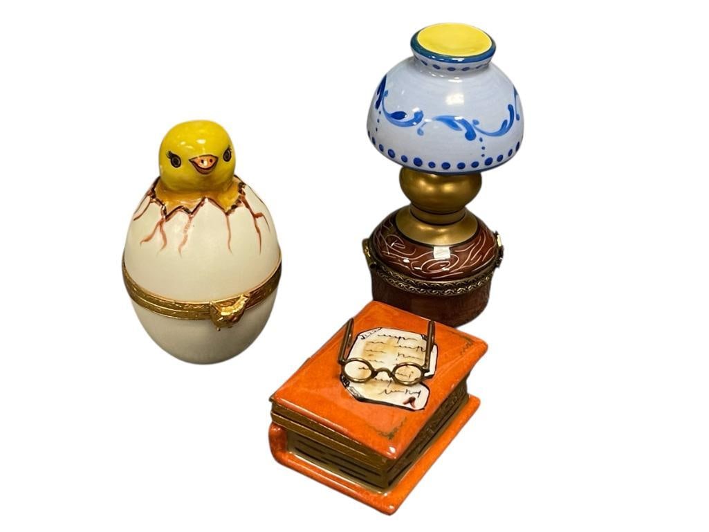 THREE HAND PAINTED PORCELAIN LIMOGES FIGURAL TRINKET / PILL BOXES: HURRICANE LAMP PILL BOX, HATCHING CHICK, AND BOOK PILL BOX, EACH WITH HINGED TOP, EACH IS ALSO HAND MARKED LIMOGES FRANCE, NO DAMAGE OR REPAIRS 1 3/4", 2 3/4", AND 3 1/4" H