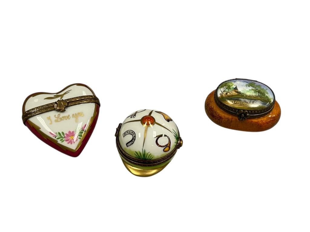 THREE PORELAIN HANDPAINTED FIGURAL LIMOGES PILL / TRINKET BOXES: JOCKEY CAP, HEART, AND JAR HINGED PILL BOXES, TWO WITH GILT ACCENTS, JAR HAS HAND PAINTED LANDSCAPE SCENE ON THE LID, EACH BOX IS MARKED LIMOGES FRANCE 1 3/4" JOCKEY CAP, 2" HEART, AND 1 7/8" JAR