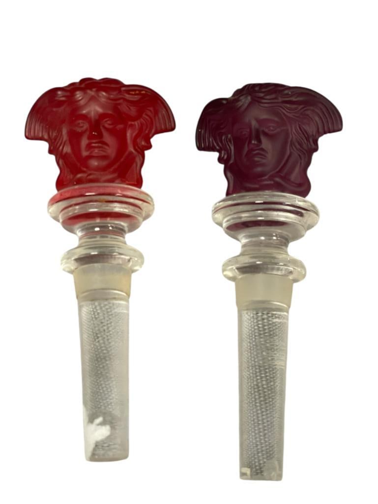 ROSENTHAL FOR VERSACE MEDUSA FROSTED LEAD CRYSTAL WINE BOTTLE STOPPERS: PURPLE AND RED FROSTED CRYSTAL STOPPERS, EACH WITH WATERMARK, BOTH STOPPERS HAVE DAMAGE TO THE END OF THE STOPPER, BUT NOT ON THE FIGURE 5" L