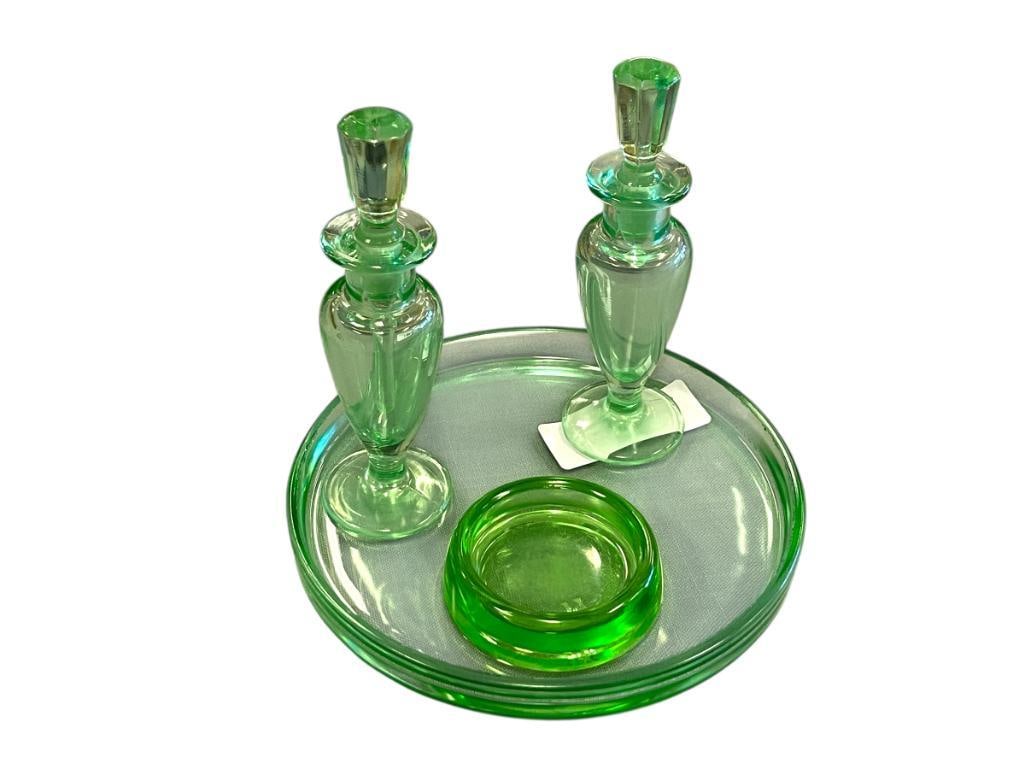 1930'S GREEN DEPRESSION GLASS FRAGRANCE / PERFUME BOTTLES WITH VANITY TRAY AND HAZEL ATLAS COASTER: MATCHING PERFUME BOTTLES WITH STOPPERS PLUS ROUND VANITY DISH, DISH HAS CHIPS ALONG THE EDGE, PLUS HAZEL ATLAS URANIUM GLASS FURNITURE COASTER 6" PERFUME BOTTLES, 7" DISH, 3" COASTER