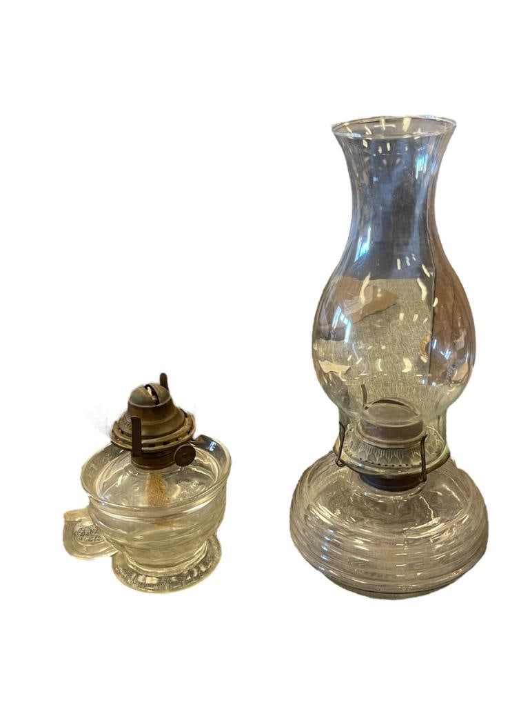 TWO ANTIQUE PRESSED GLASS OIL LAMPS: ROUND RIBBED OIL LAMP WITH CHIMNEY BY P&A AND FOOTED OIL LAMP WITH FINGER LOOP HANDLE, MISSING CHIMNEY, NO CHIPS OR CRACKS 6" AND 12" H