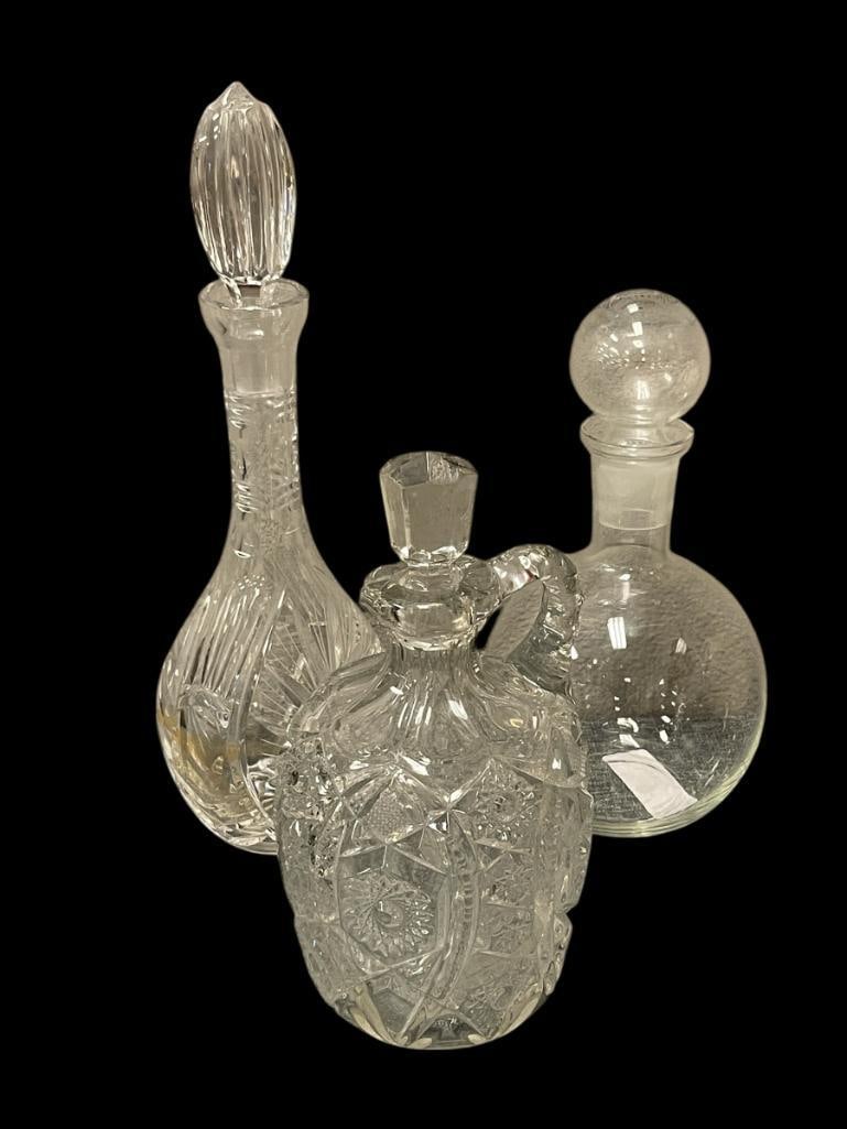 CRYSTAL AND GLASS DECANTERS: WHEEL CUT PATTERN TALL CRYSTAL DECANTER WITH STOPPER, EARLY AMERICAN PRESSED GLASS WHISKEY DECANTER CROSSHATCH / SUNBURST PATTERN, AND BULBOUS CLEAR GLASS DECANTER WITH STOPPER, EAPG DECANTER STOPPER