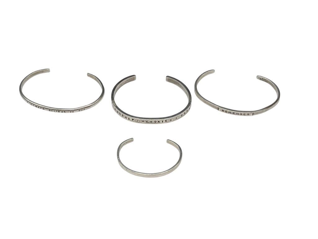 FOUR STERLING SILVER CUFF BRACELETS FEATURING THREE POSITIVE AFFIRMATION MESSAGES: TWO MARKED COMSTOCK STERLING, ONE MARKED W. MC DERMOTT VARIOUS CUFF WIDTHS, 40.68 GRAMS 
