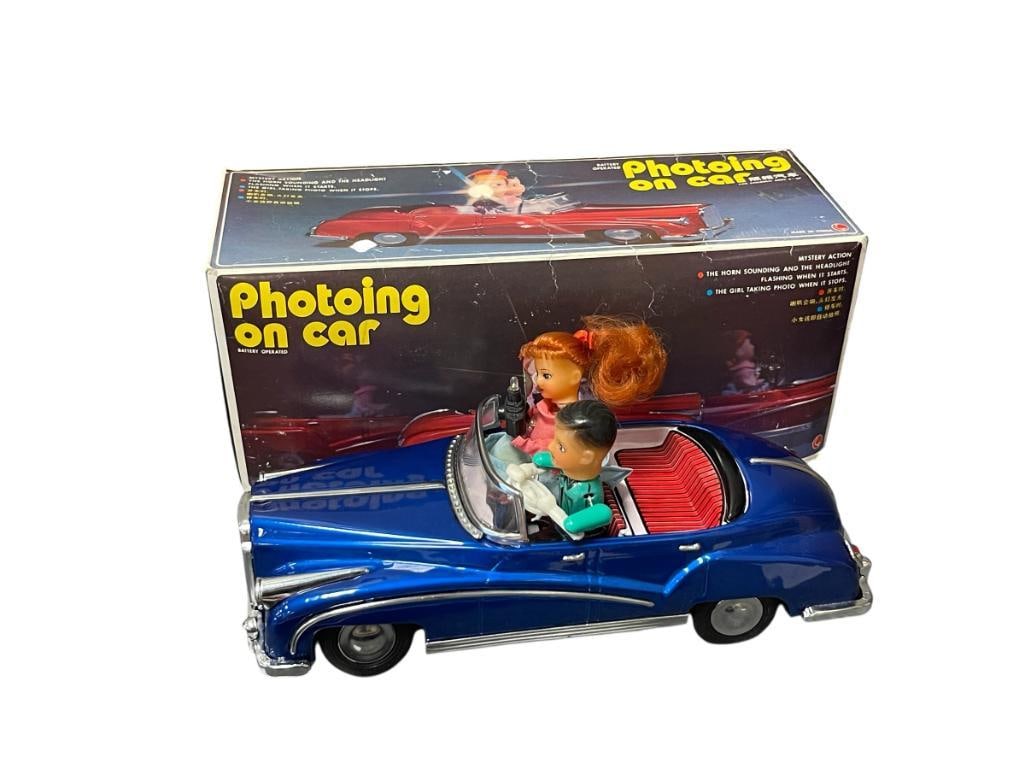 1960'S / 1970'S PHOTOING ON CAR TIN-LITHO BATTERY OPERATED TOY: WITH MYSTERY ACTION, SOUND, AND LIGHTS, NEAR MINT CONDITION INCLUDES ORIGINAL BOX, WOMANS HEAD NEEDS TO BE REATTACHED AS GLUE HAS FAILED 12" L
