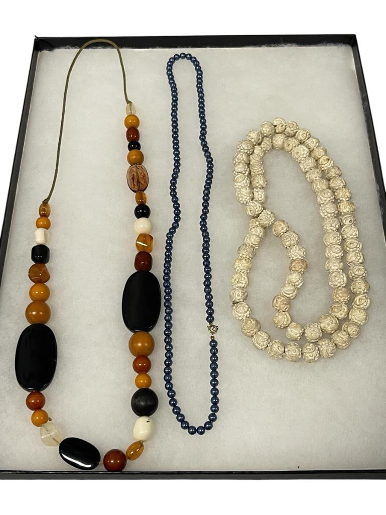 THREE WOMANS FASHION JEWELRY NECKLACES: BLUE BEADED NECKLACE, CARVED BEADED NECKLACE, AND AMBER COLORED BEADED NECKLACE 