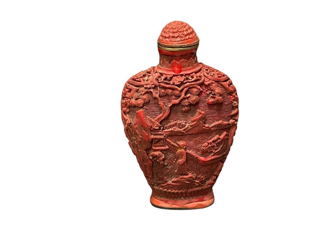 1960'S CARVED CINNABAR LACQUER CHINESE SNUFF BOTTLE IN RELIEF WITH LANDSCAPE SCENE, MARKED: INTRICATELY CARVED SNUFF BOTTLE WITH SCENE OF PEOPLE WITH LANDSCAPE SCENE IN THE BACKGROUND, MARKED ON THE BOTTOM WITH BRASS SEAL, WITH TOP AND SPOON 2 7/8" H 