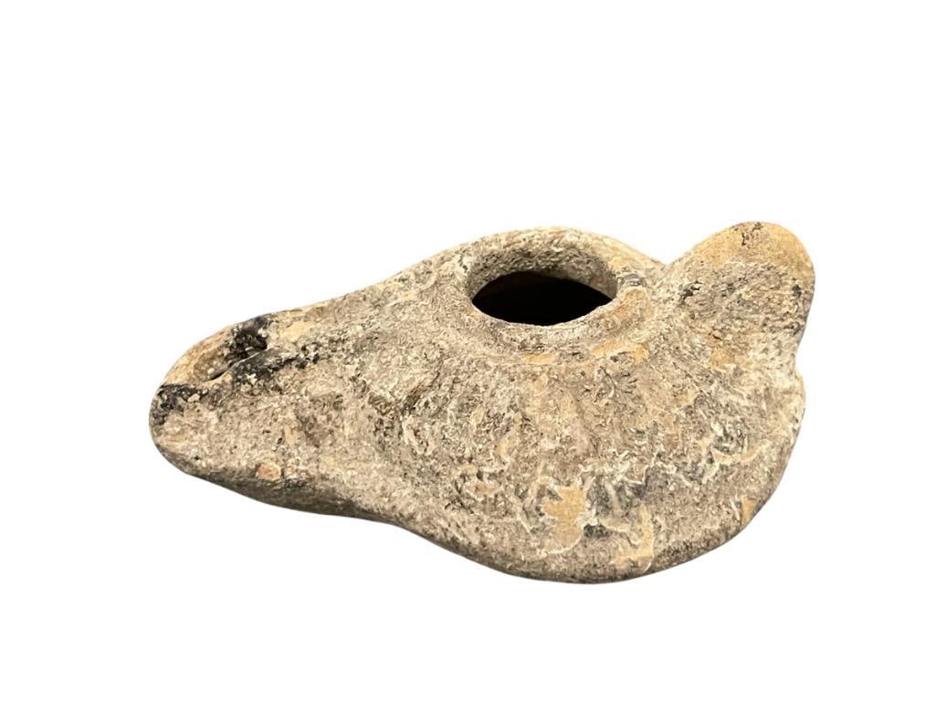 ANCIENT ROMAN / BYZANTINE TERRACOTA OIL LAMP CIRCA 5TH CENTURY: CIRCULAR OIL LAMP WITH SPOUT AND SMALL TAB-LIKE HANDLE, FEATURES DESIGN AROUND THE RESERVOIR, SPOUT DOES HAVE A SMALL CHIP ON THE SPOUT, NO MAJOR DAMAGE 3 1/4" L 
