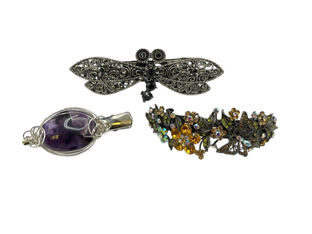 THREE COSTUME JEWELRY HAIR BARETTES INCLUDING BUTTERFLY AND DRAGONFLY DESIGNS: ALSO INCLUDES PURPLE CABOCHON STONE DESIGN LARGEST IS 5" 