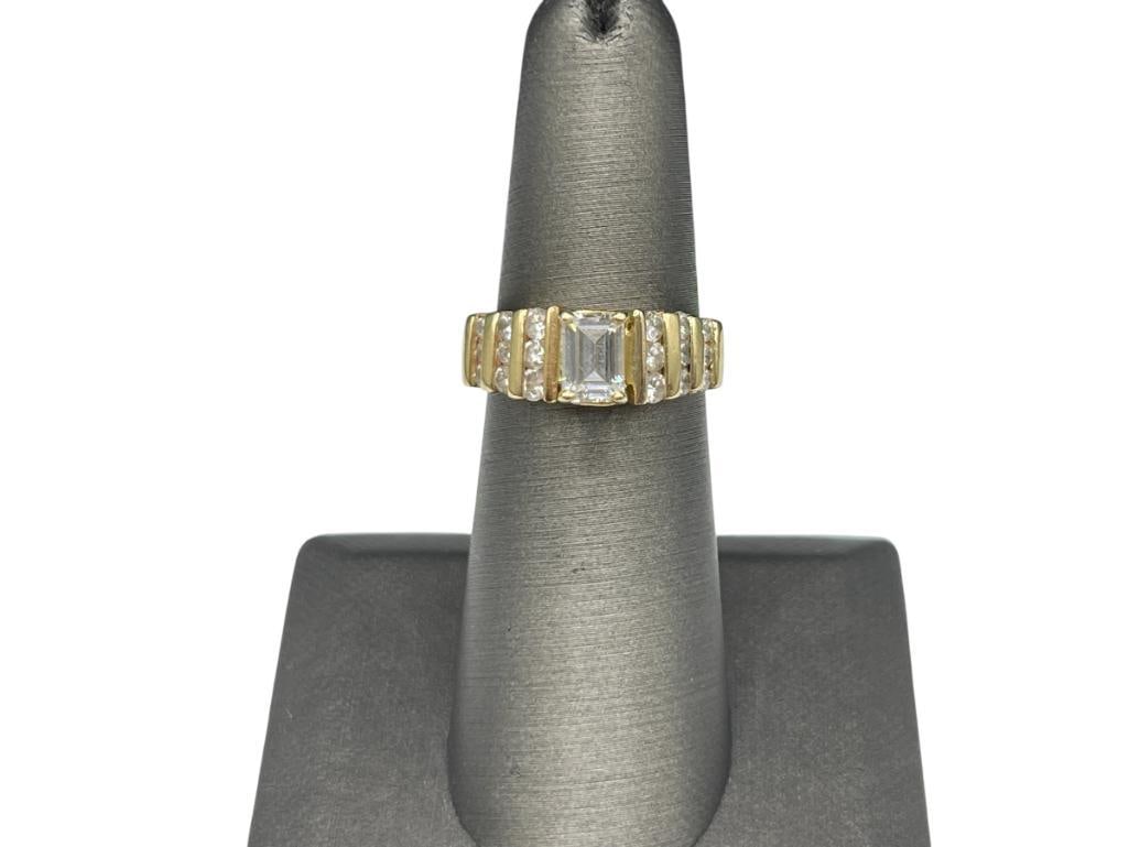 14K YELLOW GOLD RING FEATURING AN EMERALD CUT CZ ACCENTED BY 18 ROUND BRILLIANT CUT DIAMONDS: TAPERED DESIGN ON SHOULDERS OF SHANK SIZE 6, 5.33 GRAMS, 7MM CZ, UP TO 2MM DIAMONDS 