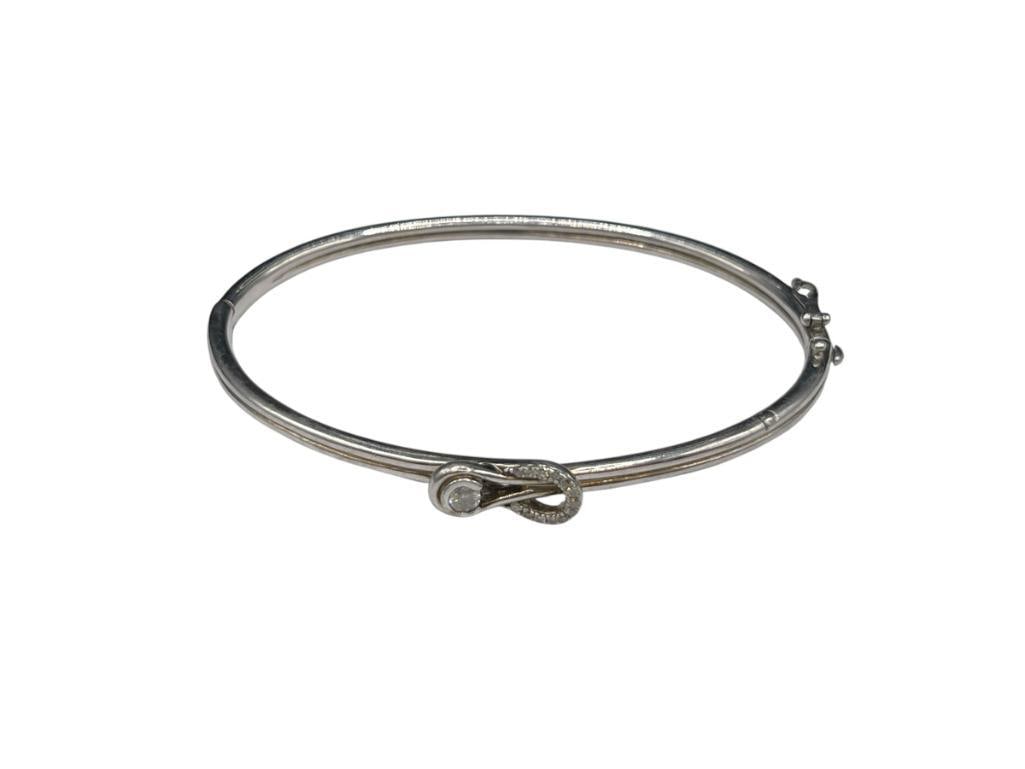 STERLING SILVER ZEI DESIGNER SIGNED DIAMOND BANGLE BRACELET: FEATURING DUAL LOOP DESIGN WITH SINGLE ROUND BRILLIANT CUT DIAMOND ON ONE SIDE AND SEVERAL ROUND BRILLIANT CUT DIAMONDS ON OTHER 2 5/8" WRIST WIDTH X 1/4" FRONT, 3MM DIAMOND AND SMALLER DIAMONDS ARE