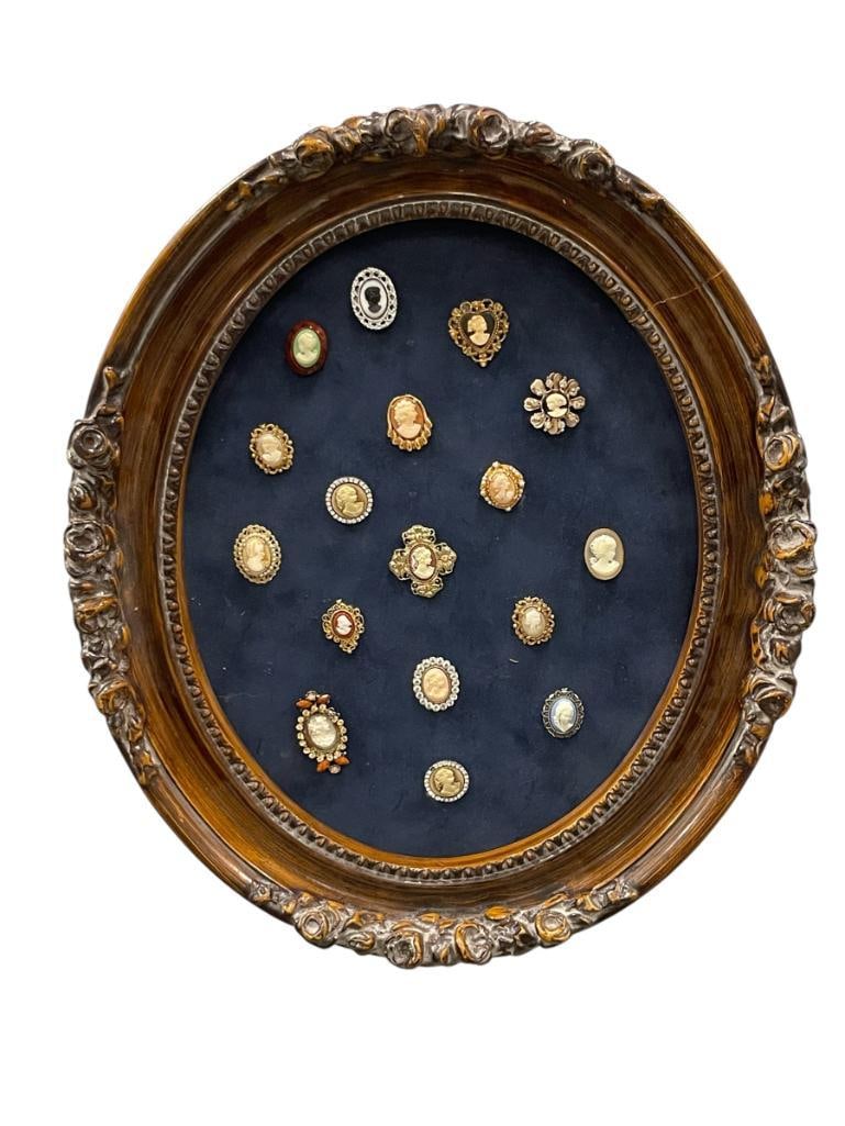 ARTISAN MADE CAMEO DISLAY FEATURES 17 CAMEOS FEW ARE BEJEWELED: SILVER AND GOLD TONE CAMEOS, MOUNTED ON INDIGO FELT IN VICTORIAN STYLED FRAME 14" X 16" FRAME, 1" UP TO 1 3/4" CAMEOS 