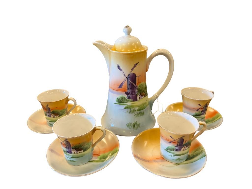 EARLY 1900'S JAPANESE PORCELAIN CHOCOLATE SET HAND PAINTED DUTCH WINDMILL LANDSCAPE SCENE: HAND PAINTED PORCELAIN CHOCOLATE SET, POT WITH FOUR CUPS AND SAUCERS, WITH GILT ACCENTS, ONE CUP HAS CHIP ON THE RIM, POT IS MARKED MADE IN JAPAN WITH RAISED STAR 8 1/2" POT, 2 5/8" CUPS, 4 3/4"