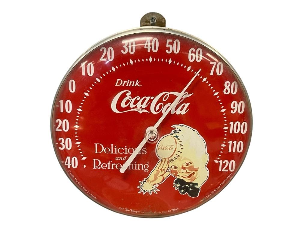 1984 THE TRU TEMP ORIGINAL JUMBO DIAL COCA-COLA THERMOMETER: RED BACKING WITH ILLUSTRATION, ACRYLIC COVER WITH TIN FRAME, LIGHT SCUFFS / SCRATCHES 12" ROUND 