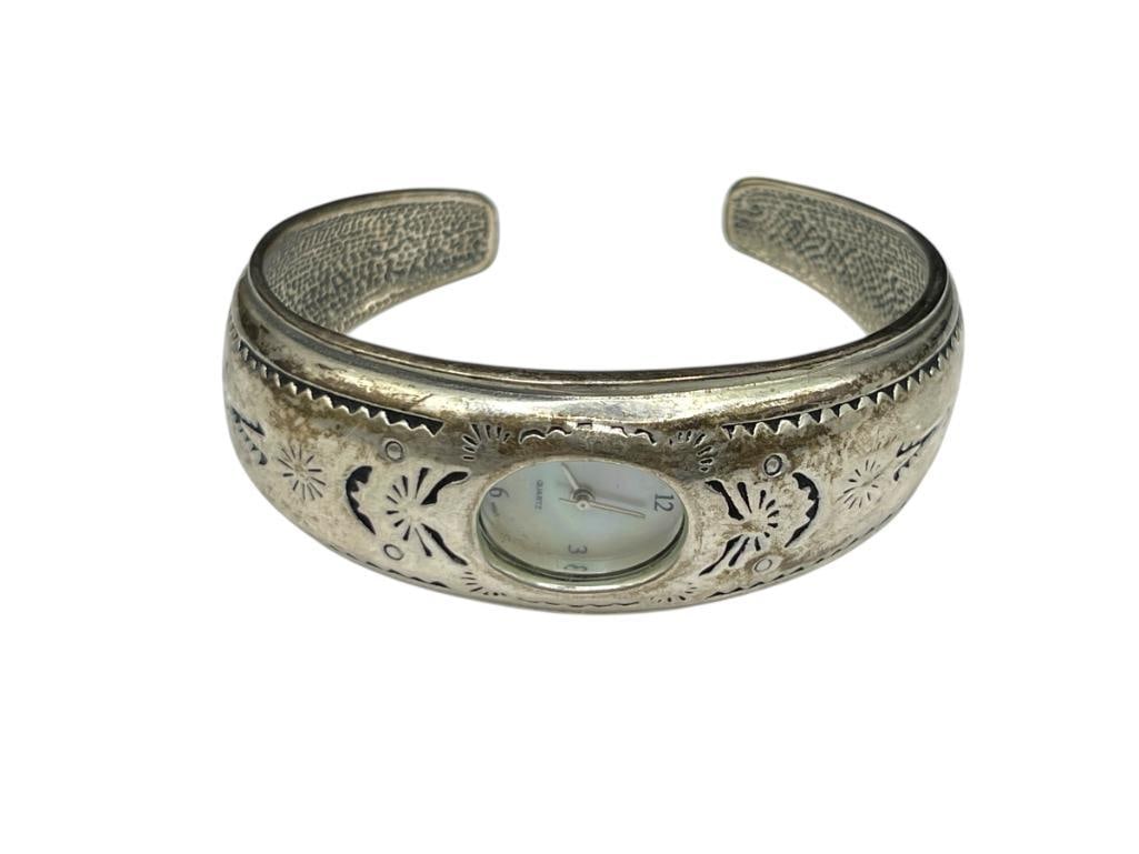 VINTAGE STERLING SILVER DESIGNER HALLMARKED WATCH CUFF WITH QUARTZ WATCH: FEATURES PIERCED SOUTHWEST DESIGN ON CUFF, MOTHER OF PEARL DIAL ON WATCH, WATCH NEEDS BATTERY 2 1/2" CUFF WIDTH, 7/8" FRONT, 51.51 GRAMS TOTAL 
