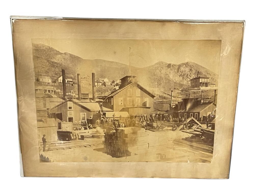 19TH CENTURY COMSTOCK PHOTGRAPH OF A MILL: PHOTOGRAPH DEPICTS MEN GATHERED IN A MILL WITH BUILDINGS IN THE BACKGROUND ALONG A MOUNTAIN SIDE 16" X 12"