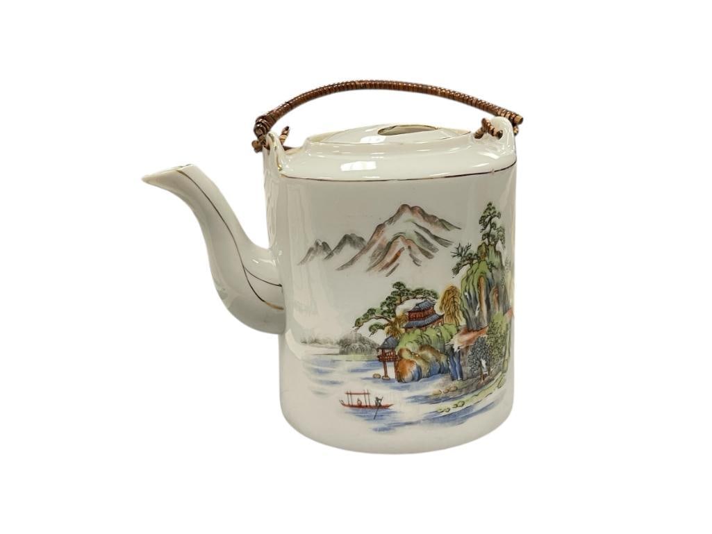 JAPANESE PORCELAIN TEAPOT WITH LANDSCAPE SCENE AND WICKER WRAPPED HANDLE: TRANSFER DECORATED, MARKED ON THE BOTTOM, NO CHIPS OR CRACKS 5 1/2" H 