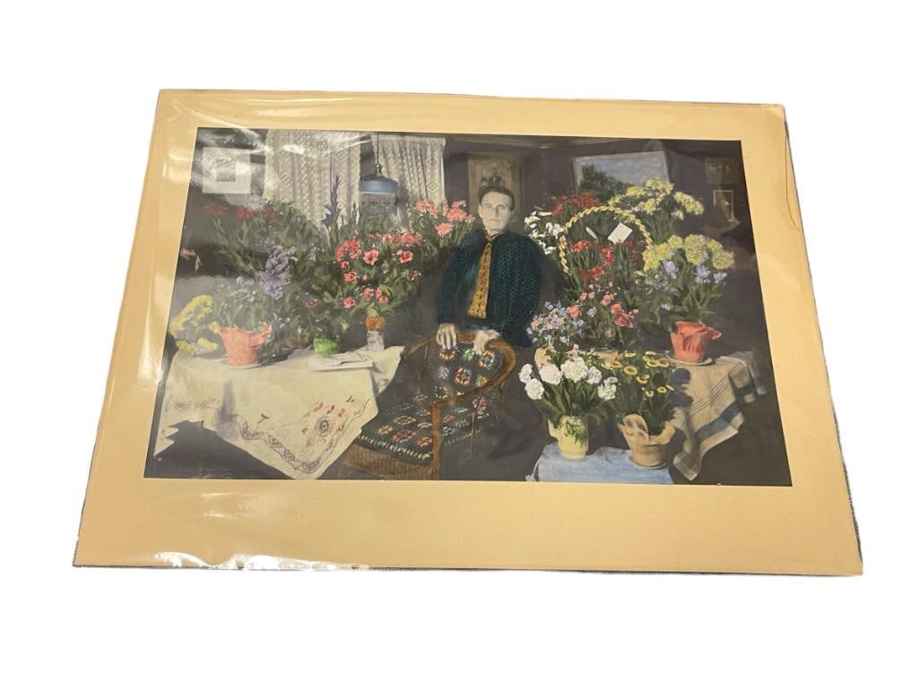 1930'S HAND COLORED PHOTOGRAPH OF A SEATED WOMAN SURROUNDED BY FLOWERS: 13 1/2" X 9" 