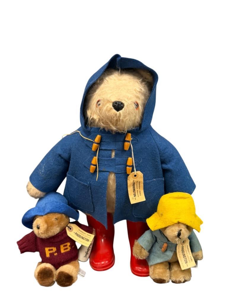EDEN TOYS INC. DARKEST PERU PADDINGTON BEARS TOTAL OF THREE: EACH BEAR HAS ITS OUTFIT, LARGE BEAR INCLUDES CLASSIC PADDINGTON ATTIRE WITH COAT AND RED RUBBER BOATS, EACH BEAR INCLUDES ORIGINAL LABELS 9" AND 20" H