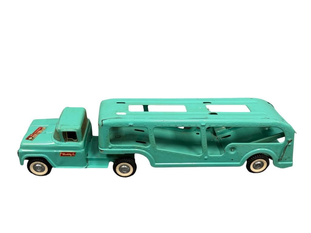 VINTAGE 1960'S BUDDY ; PRESSED STEEL AUTO TRANSPORTER CAR CARRIER WITH FRONT SPRING SUSPENSION: TURQUOISE IN COLOR WITH HARD RUBBER TIRES, ORIGINAL LABELS PRESENT INCLUDING SPRING SUSPENSION LABEL ON THE HOOD, DRIVER SIDE WINDOW IS DAMAGED AND SHOWS LIGHT PAINT WEAR 26" L