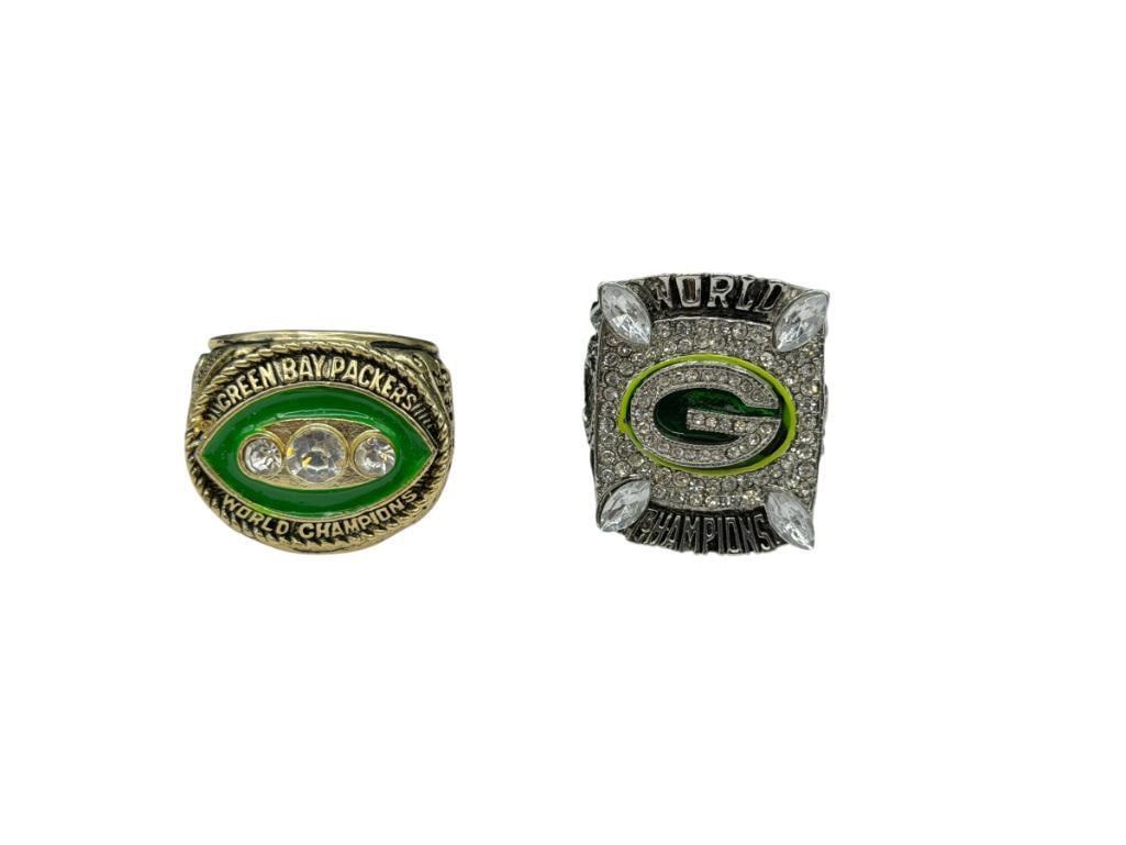 TWO GREEN BAY PACKERS NFL SUPER BOWL REPLICA RINGS INCLUDING BART STARR AND AARON RODGERS: STAINLESS STEEL DESIGN INCLUDING ONE GOLD TONE, BOTH ACCENTED WITH CLEAR STONES, FEATURING PLAYER'S NUMBERS, AND MORE INFO SIZE 13 AND SIZE 12, UP TO 1 1/8" FRONTS