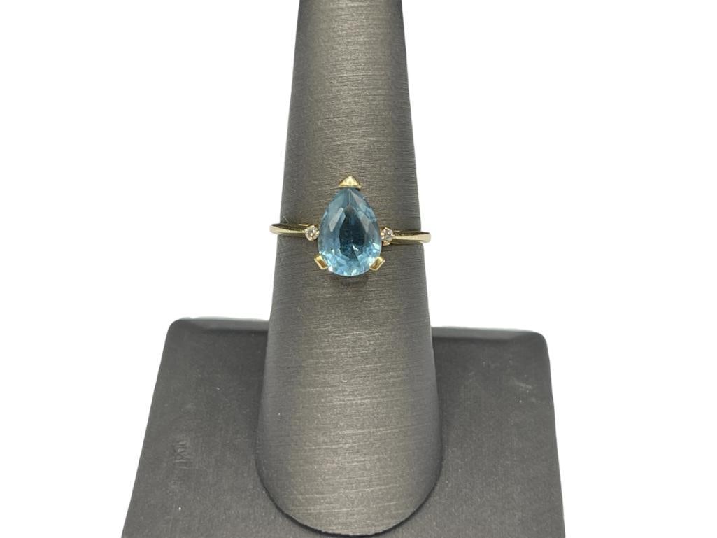14K YELLOW GOLD PEAR CUT BLUE TOPAZ AND ROUND BRILLIANT CUT DIAMOND RING: FEATURING A BLUE TOPAZ IN CENTER ACCENTED BY TWO ROUND BRILLIANT CUT DIAMONDS, DESIGNER HALLMARKED SIZE 6 1/2, 11MM X 7MM TOPAZ, 1MM DIAMONDS, 2.51 GRAMS