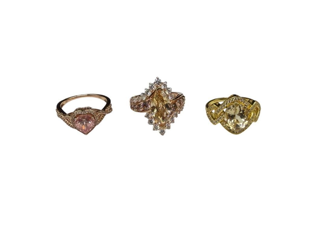 THREE STERLING SILVER ROSE GOLD PLATED AND GOLD-PLATED CZ FASHION RINGS: FEATURING CITRINE AND MORGANITE COLORED CZ'S ACCENTED BY CLEAR CZ'S VARIOUS SIZES, 11.59 GRAMS