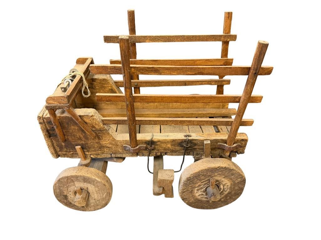 VINTAGE HAND CRAFTED WOODEN STAKE WAGON: FEATURES STAKE SIDES, SOLID WOOD WHEELS, LEATHER STRAPS TO HOLD STAKE SIDES, SHOWS AGE / WEAR 15" L