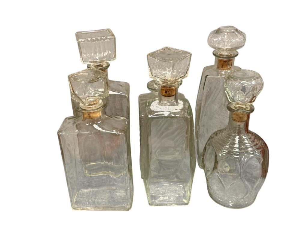 SIX VINTAGE CLEAR GLASS DECANTERS / LIQUOR BOTTES: FIVE WITH CORK STOPPERS 9 1/2" UP TO 11 1/2" H