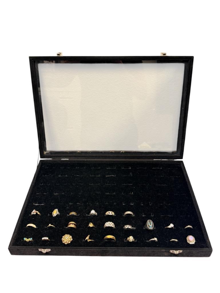 GLASS TOP JEWELRY RING CASE FEATURING 24 COSTUME JEWELRY RINGS INCLUDING VARIOUS DESIGNS: CASE IS FELT LINED AND CAN HOLD UP TO 72 RINGS CASE IS 17" X 11" X 2"