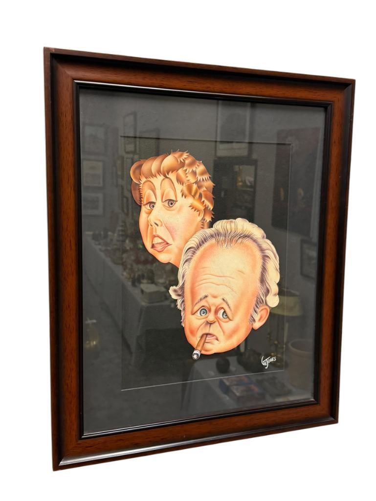 GIL JONES CARICATURE ILLUSTRATION OF ARCHIE AND EDITH BUNKER ALL IN THE FAMILY SITCOM: CUTOUT ILLUSTRATION MOUNTED ON BLACK BACKGROUND, SIGNED LOWER RIGHT, FRAMED 19" X 23" FRAME