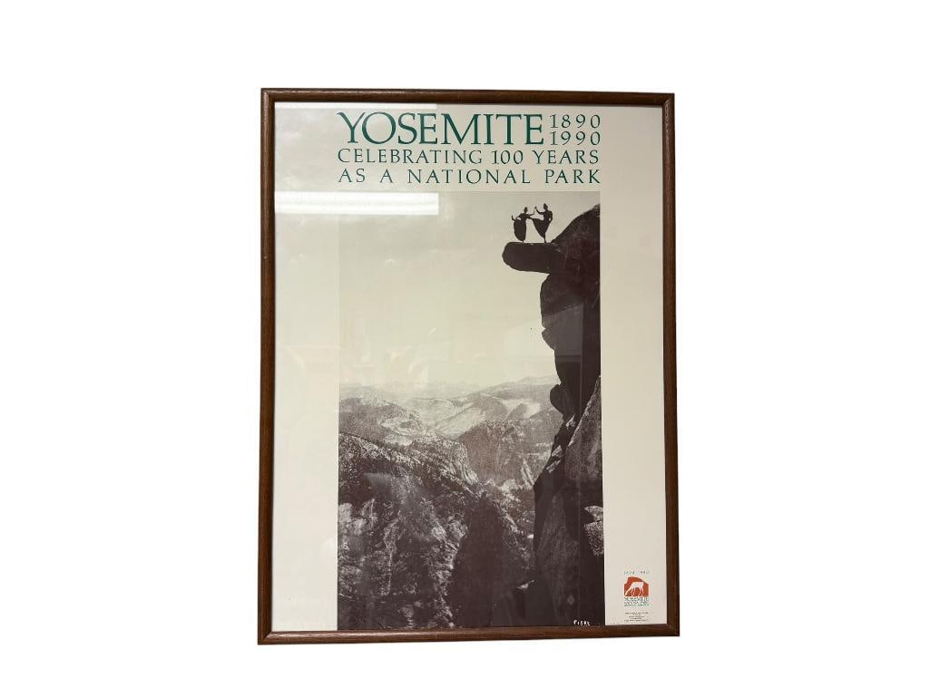 1990 YOSEMITE NATIONAL PARK CENTENNIAL CLEBRATION POSTER: "CELEBRATING 100 YEARS AS A NATIONAL PARK" FEATURING BLACK AND WHITE IMAGE OF YOSEMITE WITH TWO WOMAN JOINING HANDS ON OVERHANGING ROCK, FRAMED 19" X 25" FRAME