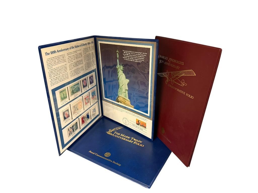 CHARLES LINDBURGH ANNIVERSARY COMMEMORATIVE STAMP PORTFOLIO AND MARK TWAIN ANNIVESARY FOLIO: ALSO INCLUDES 100TH ANNIVERSARY THE STATUE OF LIBERTY STAMP FOLIO, ALL BY THE POSTAL COMMEMORATIVE SOCIETY 8 1/2" X 10 1/2" FOLIOS