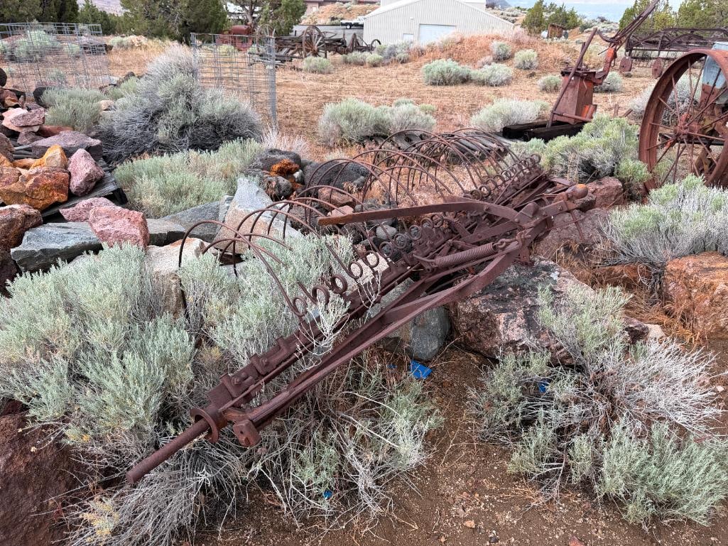 ANTIQUE FARMING IMPLEMENT HORSE DRAWN DUMP RAKE/ SULKY HAY RAKE: CIRCA LATE 19TH CENTURY, USED TO GATHER CUT GRASS OR ALFALFA INTO LONG ROWS, RUSTED FROM WEATHER, YARD ART 120" X 28" RAKE