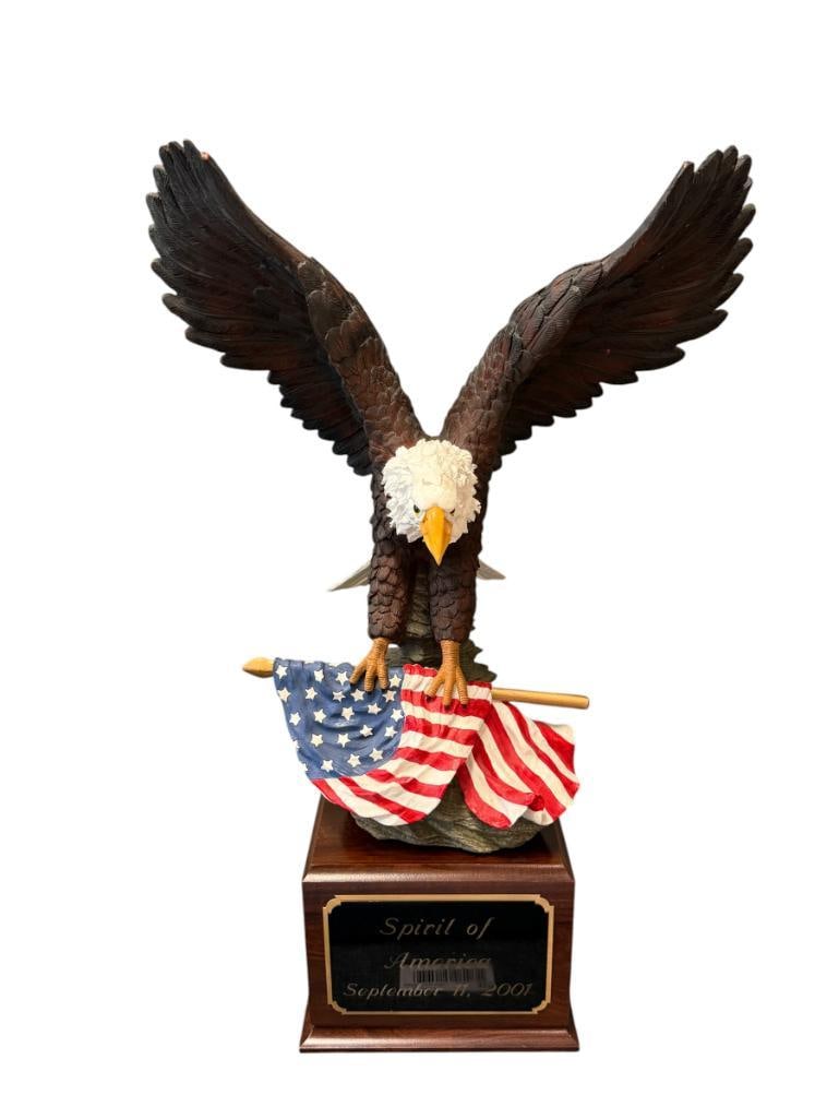 LARGE PATRIOTIC SCULPTURE OF A BALD EAGLE HOLDING AMERICAN FLAG: HEAVY RESIN SCULPTURE WITH WOODEN BASE, BASE FEATURES A PLAQUE READING "SPIRIT OF AMERICA SEPTEMBER 11, 2001" 21" TOTAL HEIGHT