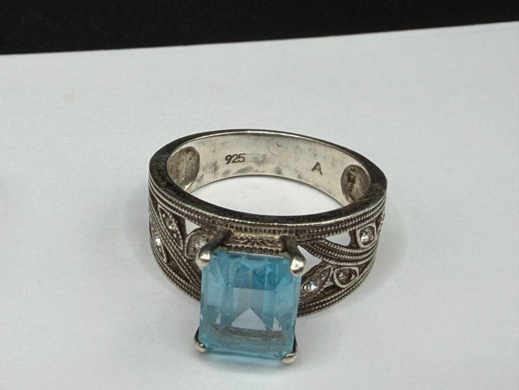 FOUR STERLING SILVER RINGS INCLUDING ONE WITH EMERALD CUT BLUE TOPAZ - 4