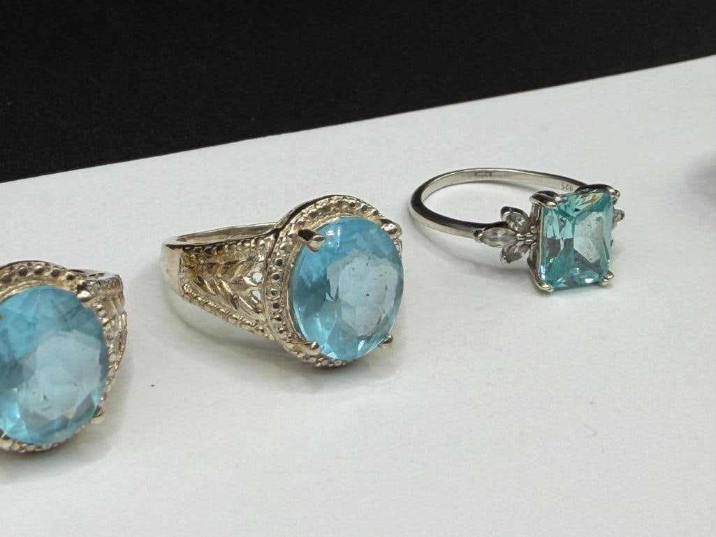 FOUR STERLING SILVER RINGS INCLUDING ONE WITH EMERALD CUT BLUE TOPAZ - 7