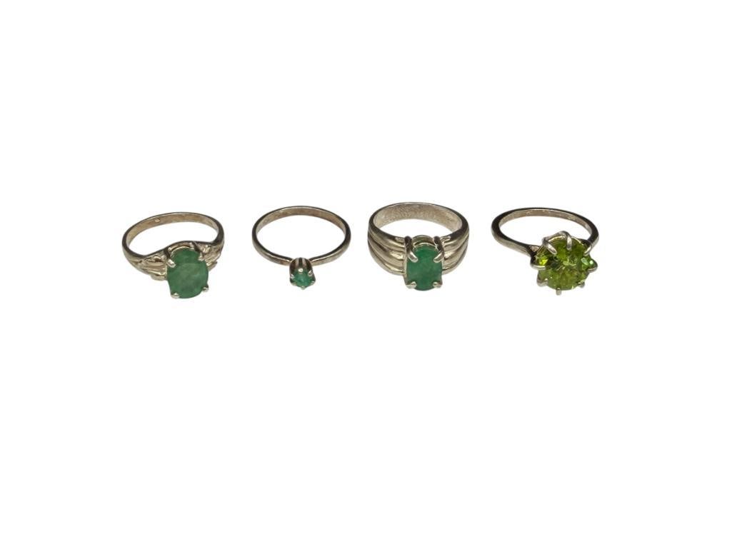 FOUR STERLING SILVER RINGS INCLUDING THREE EMERALDS AND ONE PERIDOT: FEATURING TWO OVAL CUT EMERALDS, ONE SMALL ROUND CUT EMERALD, AND A ROUND CUT PERIDOT, SOME RINGS ARE HALLMARKED VARIOUS SIZES, UP TO 10MM X 8MM OVER CUT EMERALDS, 13.18 GRAMS