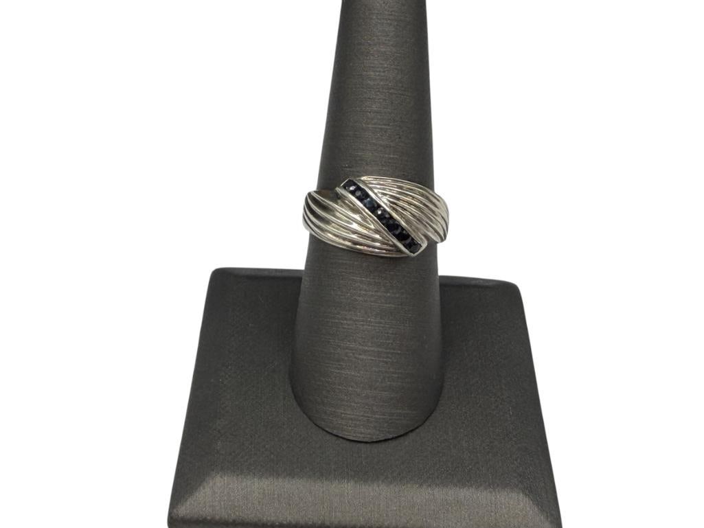 STERLING SILVER BLUE SAPPHIRE RING FEATURING CHANNEL SET ROUND CUT BLUE SAPPHIRES: FEATURES SEVEN ROUND CUT BLUE SAPPHIRES AND RIBBED DESIGN, MARKED "THAILAND" SIZE 8, 3/8" FRONT, 5.25 GRAMS, 2MM SAPPHIRES
