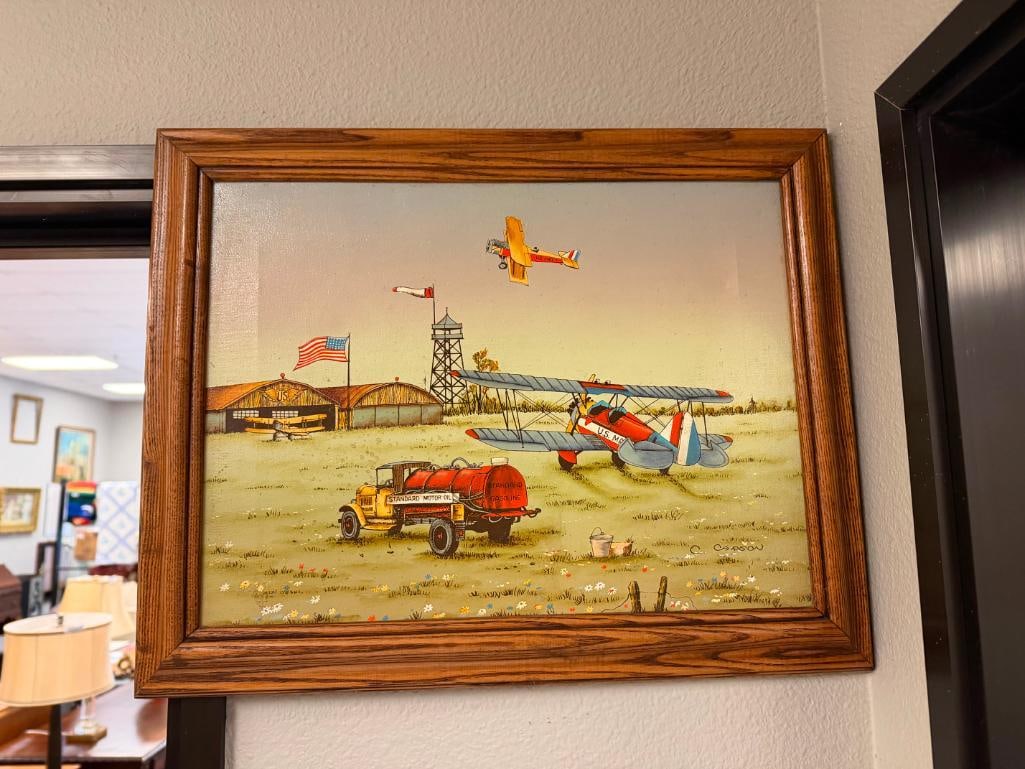 C. CARSON TEXTURED SERIGRAPH ON CANVAS DEPICTING AMERICAN THEME W/ U.S. MAIL AND STANDARD MOTOR OIL: FEATURING MID-CENTURY ERA OIL TRUCK AND PLANES AT U.S. MAIL RUNWAY, OAK FRAMED, INCLUDES ARTISTIC INTERIORS LABEL ON BACK, CANVAS SHOWS LINES FROM FRAMING 19" X 15" FRAME