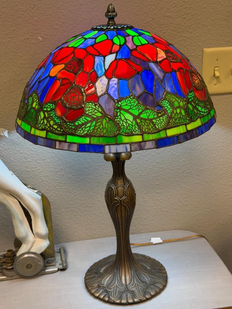TIFFANY STYLE STAINED GLASS TABLE LAMP WITH PIERCED METAL OVERLAY CAST BRONZE TONED BASE: MULTICOLOR FLORAL DESIGN SHADE WITH PIERCED DESIGN OVERLAY ON THE SHADE, DECORATIVE LEAF DESIGN BASE, TESTED + 24" H