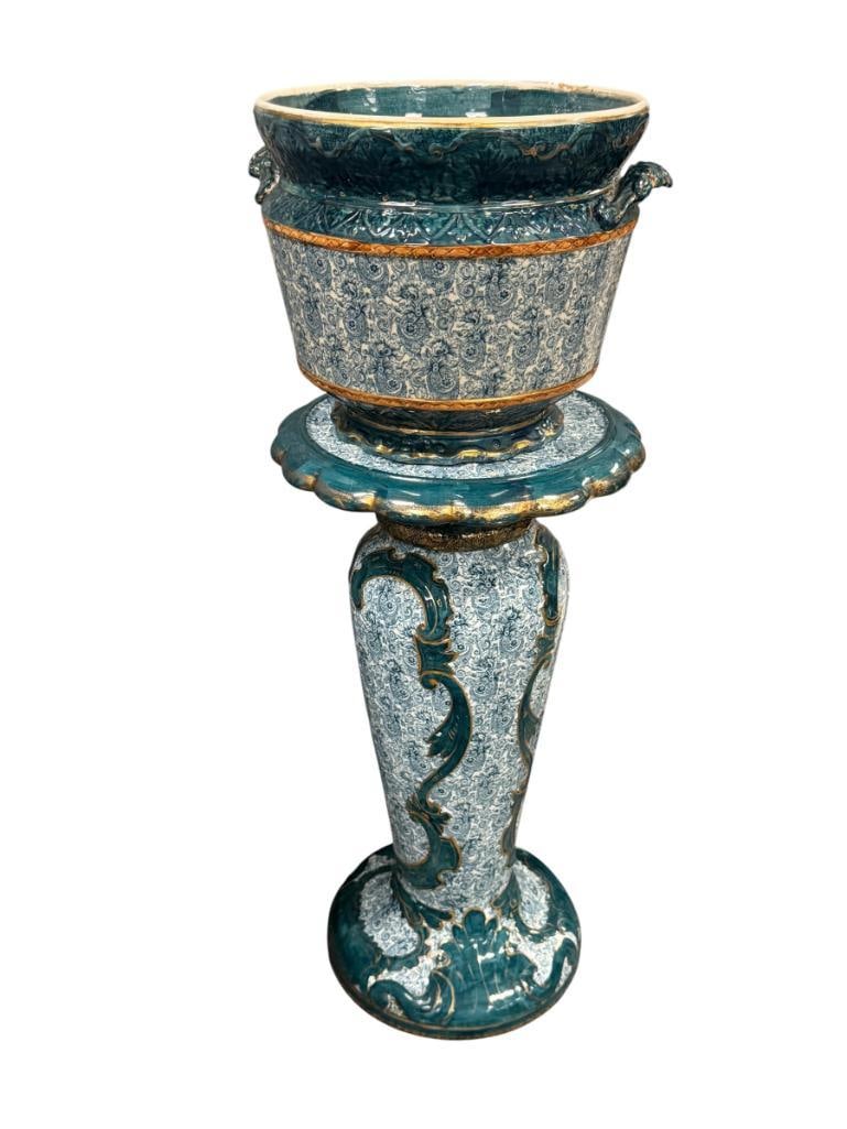 ANTIQUE MAJOLICA JARDINIERE TEAL AND GREEN GROUND WITH ELABORATE FLORAL PATTERN AND GILT ACCENTS: BASIN FEATURES DECORATIVE SCROLLING WITH ORNATE HANDLES, MATCHING COLUMN PEDESTAL, ART NOUVEAU INSPIRED, NO CRACKS OR CHIPS 34" TOTAL HEIGHT, 10" H BASIN