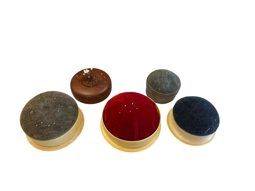 FIVE VINTAGE PIN CUSHIONS INCLUDING THREE WITH FRENCH IVORY CELLULOID BOTTOMS: ONE HAS CALIFORNIA REDWOOD BURL BASE WITH LABEL FROM REX'S OF EUREKA, CALIFORNIA, ONE IS MARKED MADE IN JAPAN WITH TIN BASE AND STORAGE LID TOP, GLASS ON THIS PIECE HAS CRACKED, VARIOUS FELT TOP