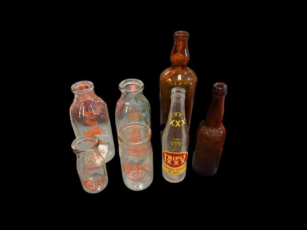 SEVEN ASSORTED ANTIQUE GLASS BOTTLES INCLUDING VALLEY DAIRY AND CRYSTAL MILK BOTTLES: ALSO INCLUDES GRAINBELT AMBER BEER BOTTLE, SELECT QUALITY "LADY'S LEG," CRESCENT MILK BOTTLE OF RENO, NEVADA, AND MORE, NO CHIPS OR CRACKS LARGEST IS 12 1/2" H