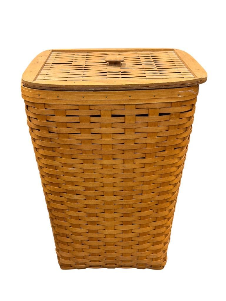 1994 LONGABERGER HAND WOVEN MAPLE LAUNDRY BASKET WITH LID AND PLASTIC LINER SIGNED ON THE BOTTOM: BASKET SHOWS A LITTLE AGE, LIGHT FRAYING ON THE LID, MISSING KNOBS ON THE BOTTOM OF THE LID 17" X 17" X 22"