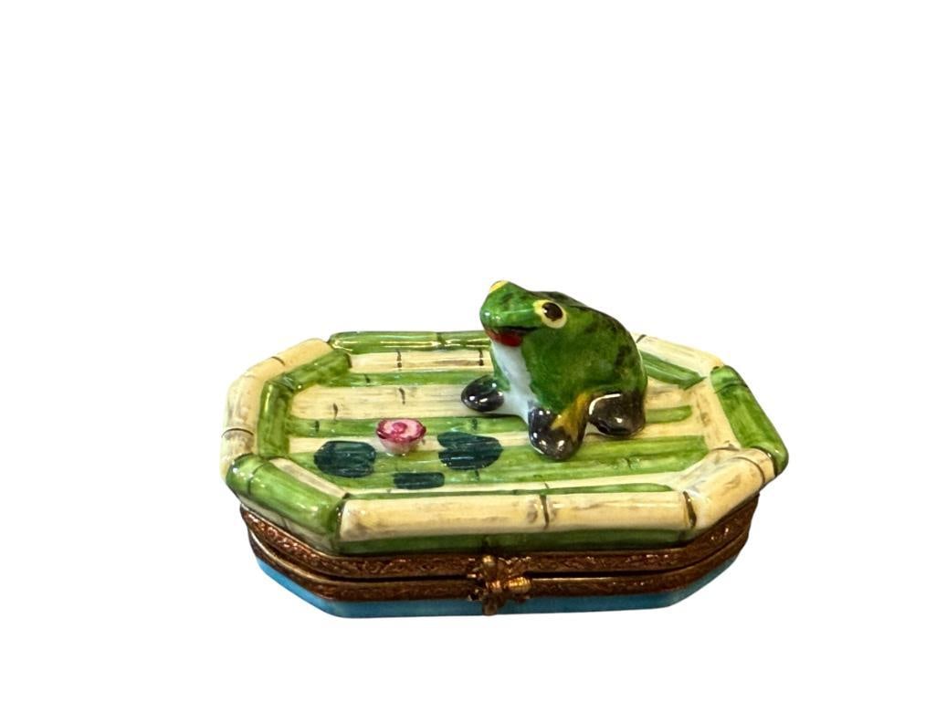 ROCHARD PORCELAIN HAND PAINTED LIMOGES TRINKET BOX: HINGED TOP TRINKET BOX WITH FROG SITTING ON BAMBOO-STYLED RAFT, MARKED ON THE BOTTOM, NO DAMGE OR REPAIR 2 1/2" L