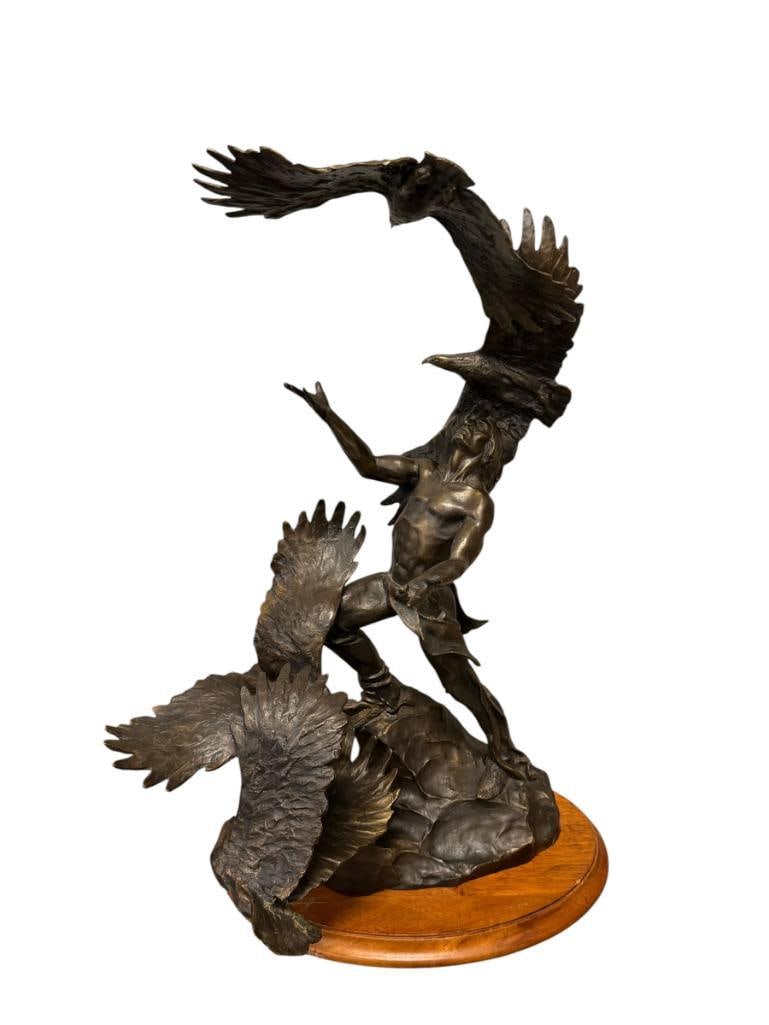 BUCK MCCAIN FOR FRANKLIN MINT BRNZE SCULPTURE THE SOARING SPIRITS: CHEYENNE INDIAN MAN WITH EAGLES FLYING AROUND HIM, SIGNED ON THE BACK OF THE SCULPTURE BY THE ARTIST, INCLUDES OVAL WOD BASE 20 1/4" H