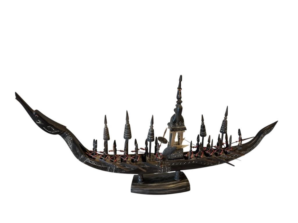 VINTAGE SUPHANNAHONG THAI CARVED WATER BUFFALO HORN ROYAL BARGE DRAGON SHIP: SHIP FEATURES 23 FIGURES ROWING / PADDLING A DRAGON BOAT WITH INTRICATE CARVINGS, MOUNTED ON HORN BASE, MISSING TWO FIGURES 28" L, 14 1/2" H 