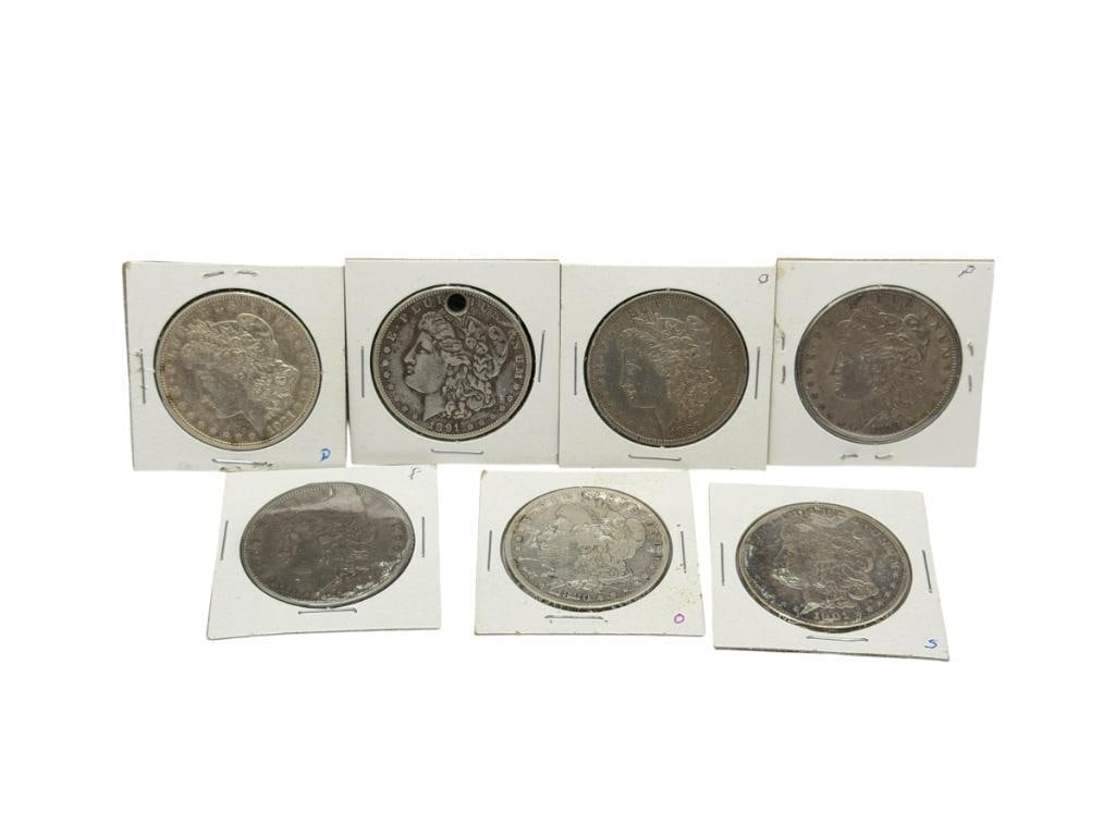 SEVEN U.S. MORGAN SILVER DOLLARS FEATURING VARIOUS DATES AND MINT MARKS: INCLUDES 1880-O, 1884, 1885-O, 1899, 1901-S, 1921-D, AND HOLED 1921, 90% SILVER